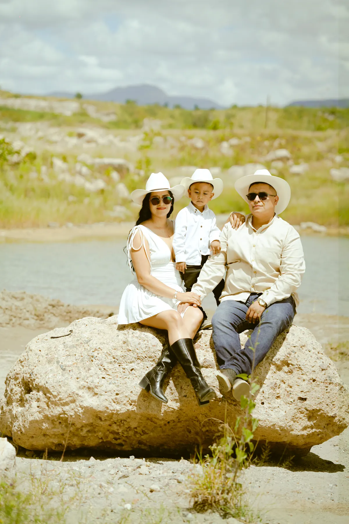 Julieta, Moisés y su hijo sentados en una roca junto al agua